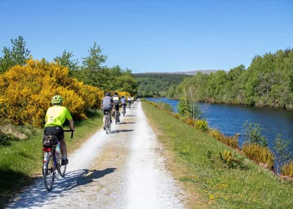 Group of cyclists on a towpath alongside the Caledonian Canal on a cycling tour along The Caledonia Way