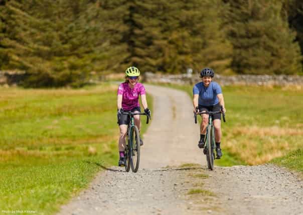 Female cyclists riding a gravel trail in Northumberland