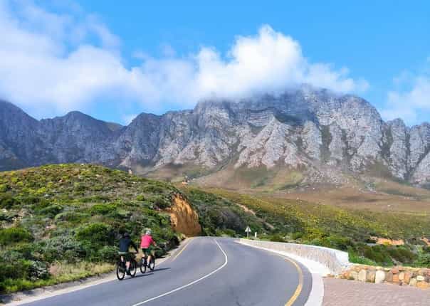 Cyclists on Clarence Drive in South Africa with views of Table Mountain