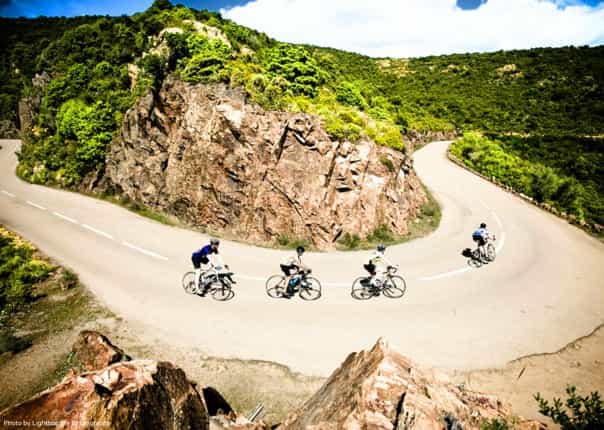 Group of road cyclists navigating a turn in Corsica, France on a cycling tour
