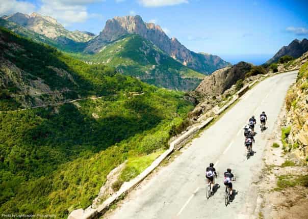 Group of road cyclists on a guided tour ascending a mountain road in Corsica, France