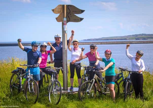 Group of happy cyclists celebrating finishing the Hadrian's Cycleway route
