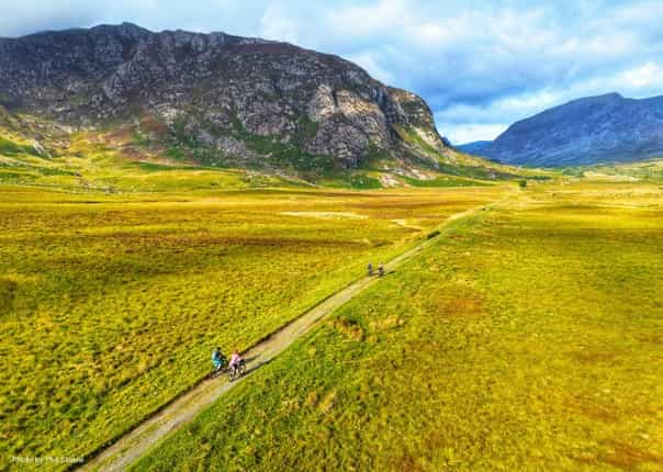 Cyclists riding past the Glyderau mountains in Wales