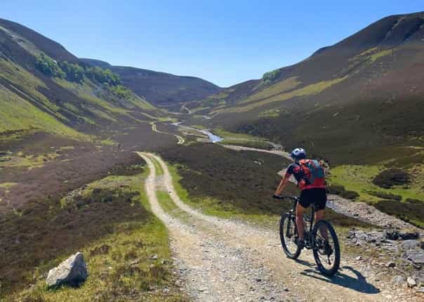 Cyclist mountain biking a trail in the Scottish Highlands on a guided tour