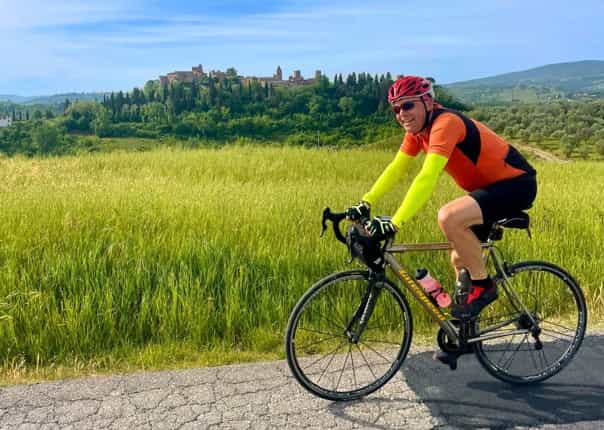 Happy road cyclist riding in Tuscany, Italy on a cycling tour