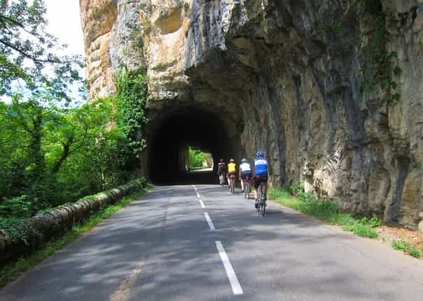 Group of road cyclists riding through a rock tunnel in Dordogne, France on a guided cycling tour