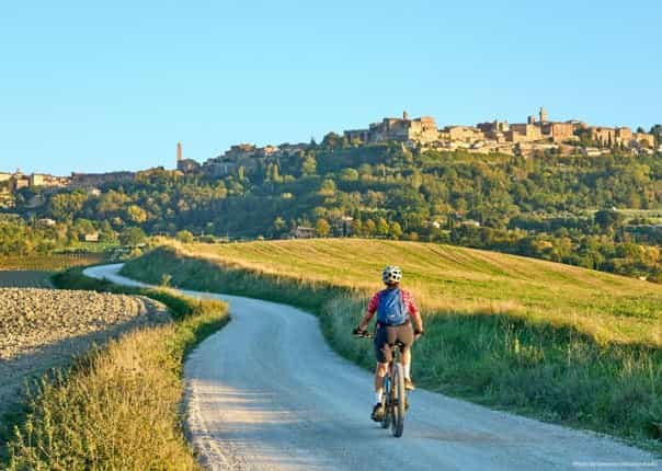 Woman mountain biking in Tuscany towards a town