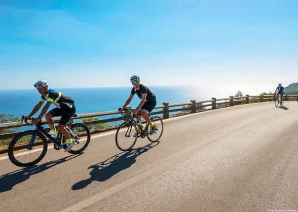 Group of road cyclists riding along a coastal road in Portugal on a guided tour