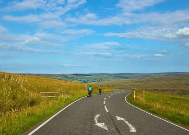 Cyclists riding a winding road in Northern England on the coast to coast cycle route